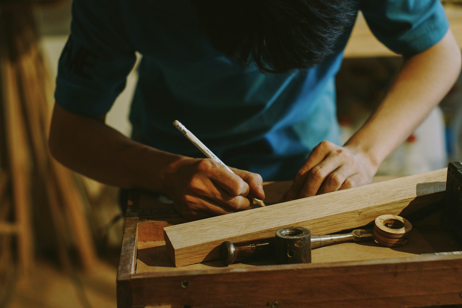 Un artisan trace une mesure sur une pièce de bois dans son atelier